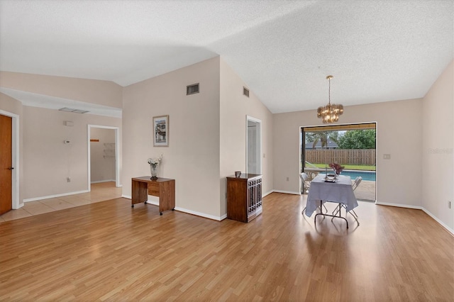 dining area featuring a textured ceiling, light hardwood / wood-style flooring, vaulted ceiling, and a notable chandelier