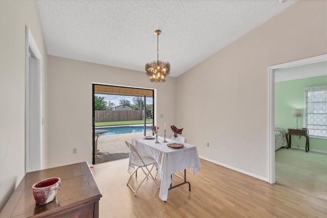 dining room featuring light hardwood / wood-style floors, a textured ceiling, and an inviting chandelier