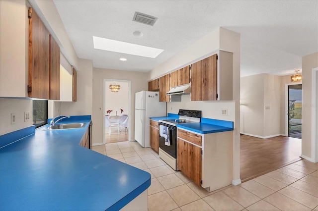 kitchen featuring a skylight, white appliances, sink, light hardwood / wood-style flooring, and a notable chandelier