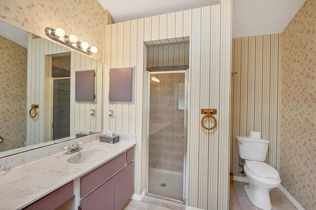 bathroom featuring tile patterned floors, vanity, toilet, and walk in shower