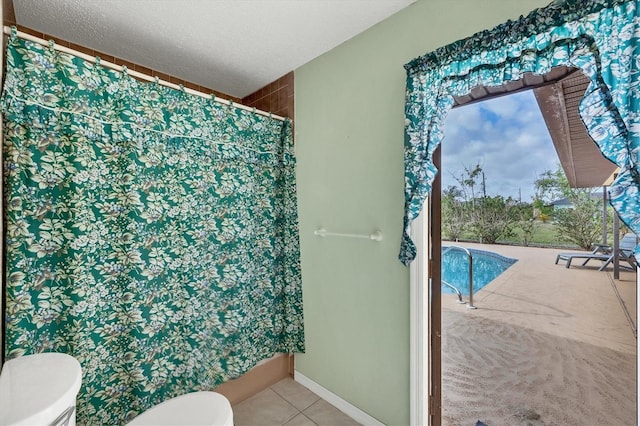 bathroom featuring tile patterned floors, toilet, and a textured ceiling