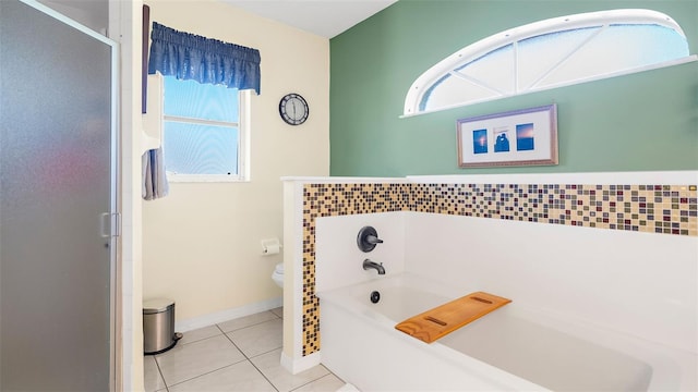 bathroom featuring a tub, toilet, plenty of natural light, and tile patterned flooring