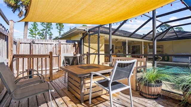 wooden deck with a fenced in pool, glass enclosure, and ceiling fan