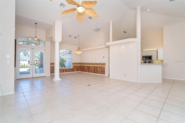 unfurnished living room featuring ceiling fan with notable chandelier, light tile patterned floors, high vaulted ceiling, and french doors