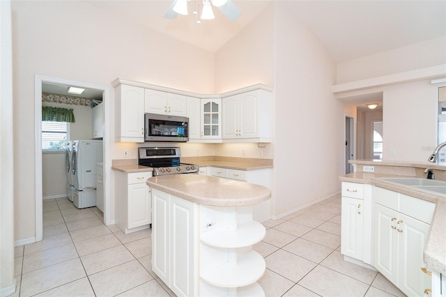 kitchen featuring washing machine and clothes dryer, sink, white cabinets, and stainless steel appliances