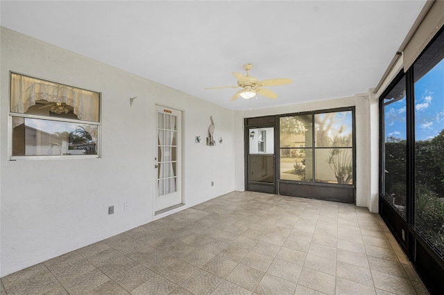 unfurnished sunroom with ceiling fan and plenty of natural light