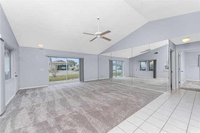 unfurnished living room with plenty of natural light, ceiling fan, light colored carpet, and high vaulted ceiling