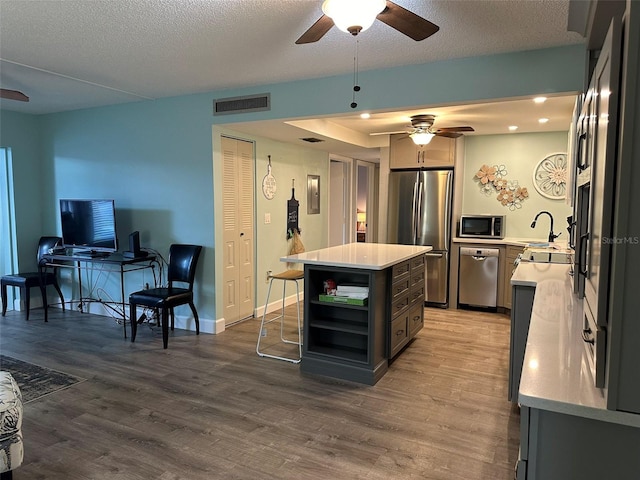 kitchen with a kitchen island, stainless steel appliances, a textured ceiling, and wood-type flooring