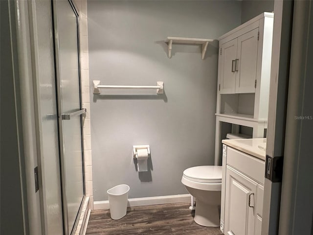 bathroom with hardwood / wood-style flooring, vanity, toilet, and a shower with shower door