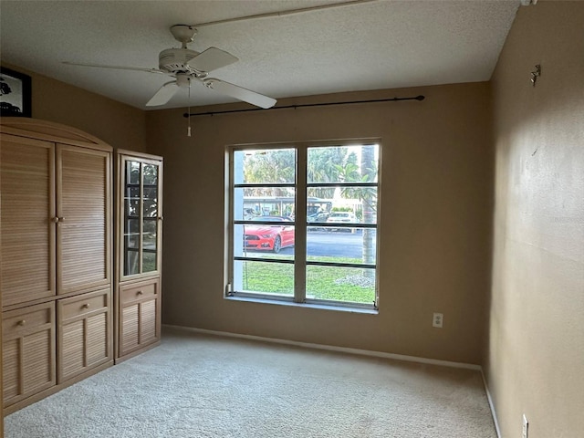 carpeted empty room with ceiling fan and a textured ceiling