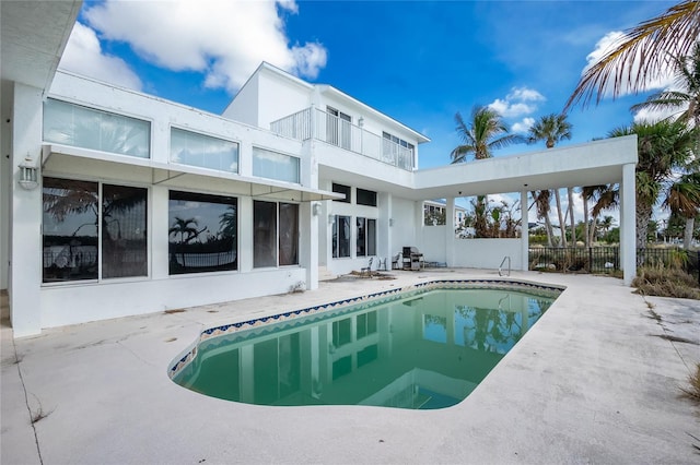 rear view of property featuring a fenced in pool and a patio area