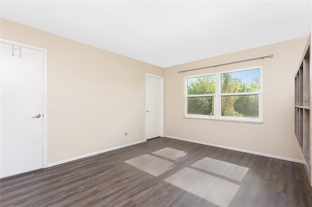 empty room featuring dark wood-type flooring and a textured ceiling