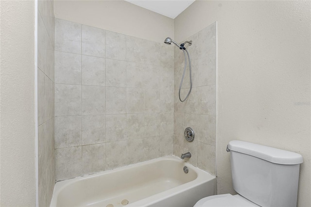 bathroom with toilet and tiled shower / bath