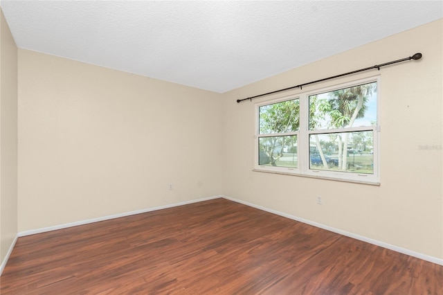 spare room featuring a textured ceiling and dark wood-type flooring