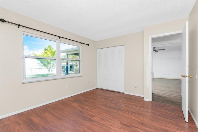 unfurnished bedroom featuring a textured ceiling, dark hardwood / wood-style flooring, and a closet