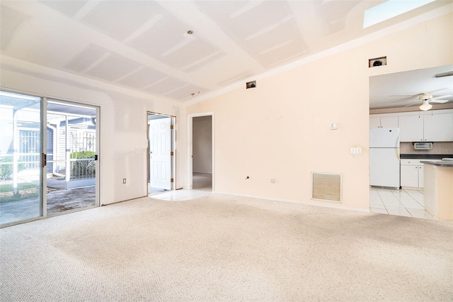 spare room featuring ceiling fan, light carpet, and vaulted ceiling