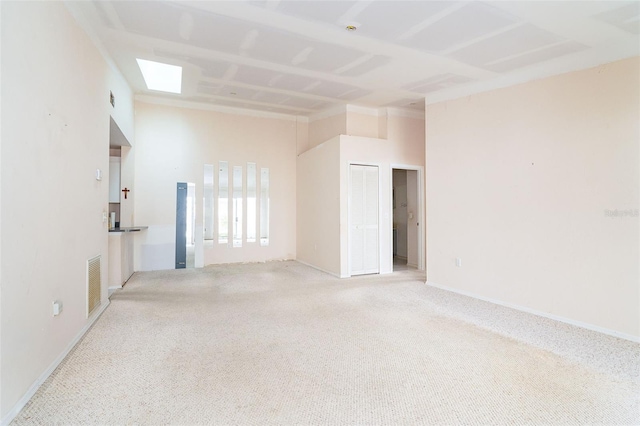 carpeted empty room featuring a high ceiling and a skylight