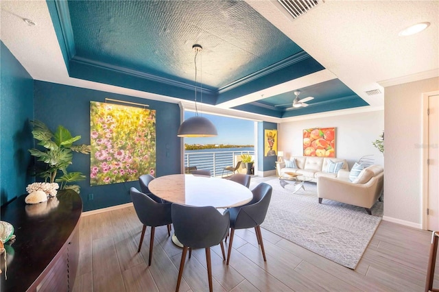 dining space with hardwood / wood-style floors, a raised ceiling, ceiling fan, and crown molding