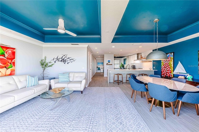 living room featuring hardwood / wood-style floors, ceiling fan, sink, and crown molding