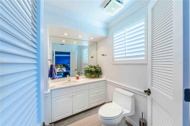 bathroom featuring vanity, toilet, ornamental molding, and wood-type flooring