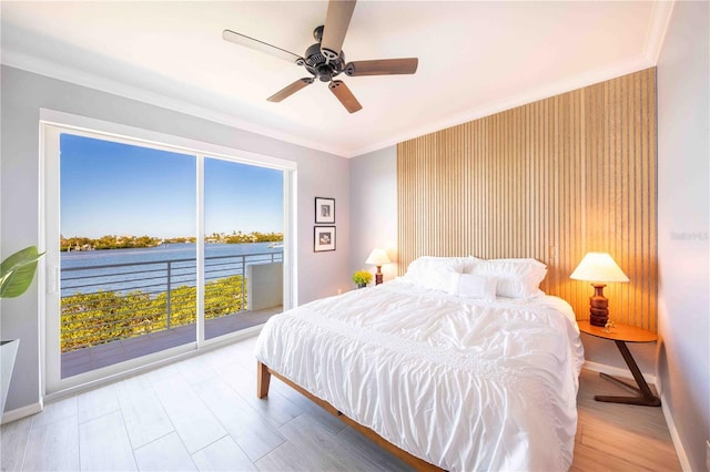 bedroom featuring access to exterior, ceiling fan, crown molding, multiple windows, and a water view