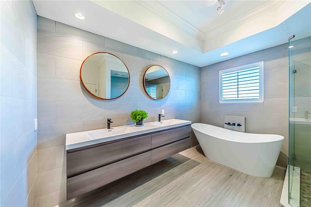 bathroom with crown molding, wood-type flooring, vanity, independent shower and bath, and tile walls