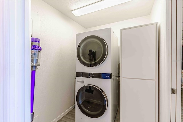 laundry room with stacked washer and dryer and hardwood / wood-style flooring