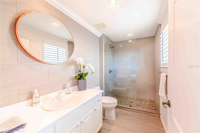 bathroom featuring a tile shower, vanity, wood-type flooring, and toilet