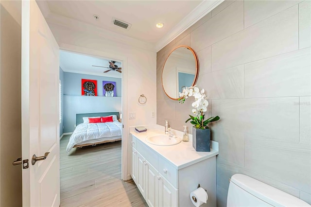 bathroom featuring vanity, ceiling fan, crown molding, tile walls, and toilet