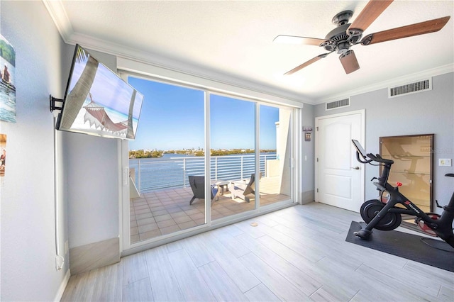 workout room featuring light wood-type flooring, ceiling fan, and crown molding