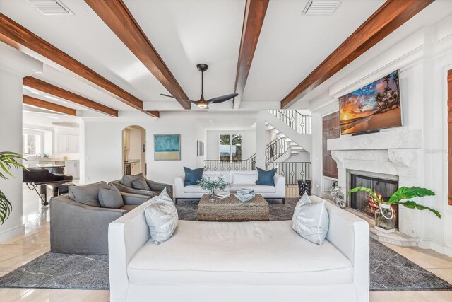 living room with beamed ceiling, ceiling fan, light tile patterned floors, and a high end fireplace