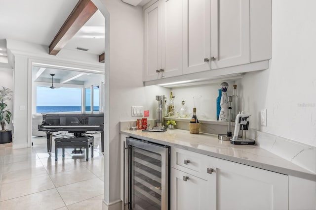 bar with beamed ceiling, a water view, white cabinetry, and beverage cooler