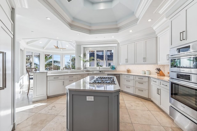 kitchen with ceiling fan, ornamental molding, kitchen peninsula, a kitchen island, and appliances with stainless steel finishes