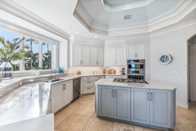 kitchen with sink, stainless steel appliances, a raised ceiling, crown molding, and a kitchen island