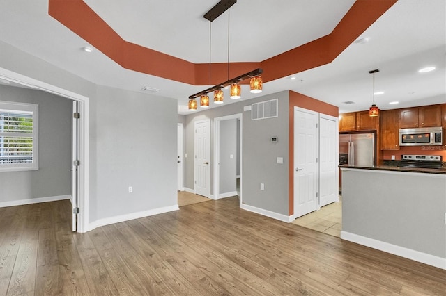 interior space featuring stainless steel appliances, light hardwood / wood-style floors, and hanging light fixtures