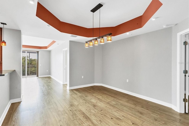 empty room with hardwood / wood-style flooring and a raised ceiling