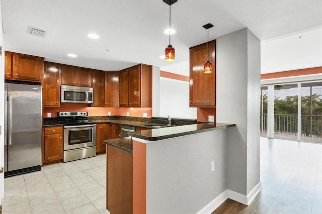 kitchen with sink, kitchen peninsula, dark stone counters, hanging light fixtures, and appliances with stainless steel finishes