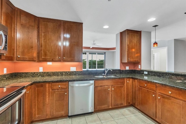 kitchen with dark stone countertops, stainless steel appliances, ceiling fan, sink, and decorative light fixtures