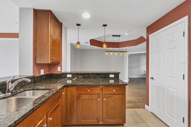 kitchen featuring sink, decorative light fixtures, dark stone countertops, light tile patterned floors, and kitchen peninsula