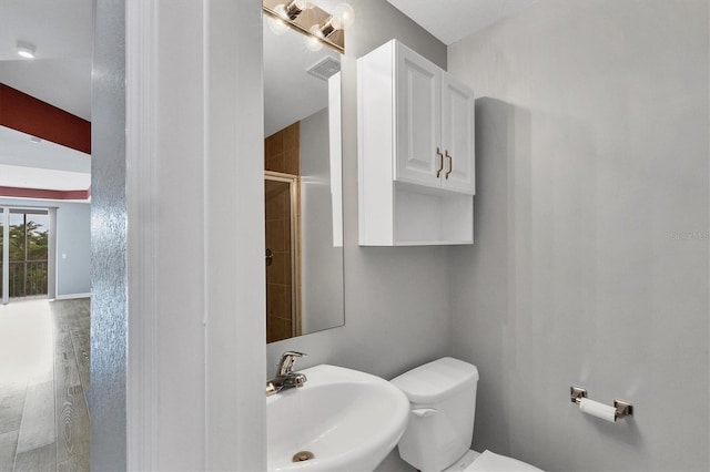 bathroom with toilet, hardwood / wood-style flooring, an enclosed shower, and sink