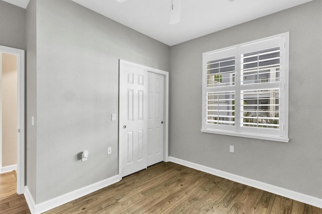 unfurnished bedroom featuring ceiling fan, a closet, and hardwood / wood-style floors