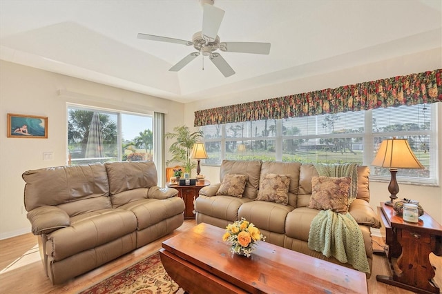 living room featuring a raised ceiling, ceiling fan, and light hardwood / wood-style floors