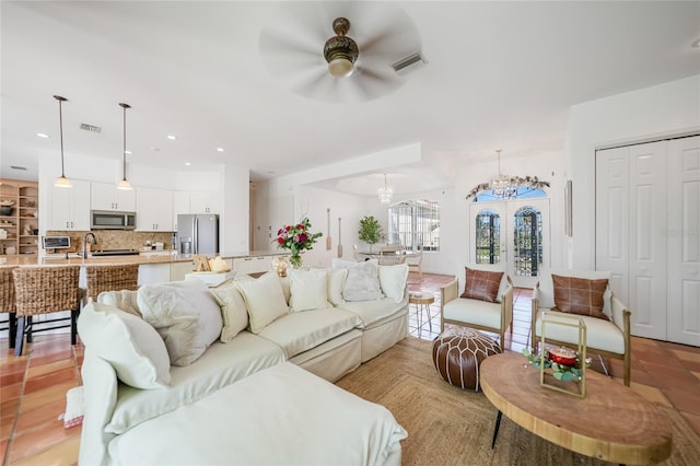 living room with french doors and ceiling fan with notable chandelier