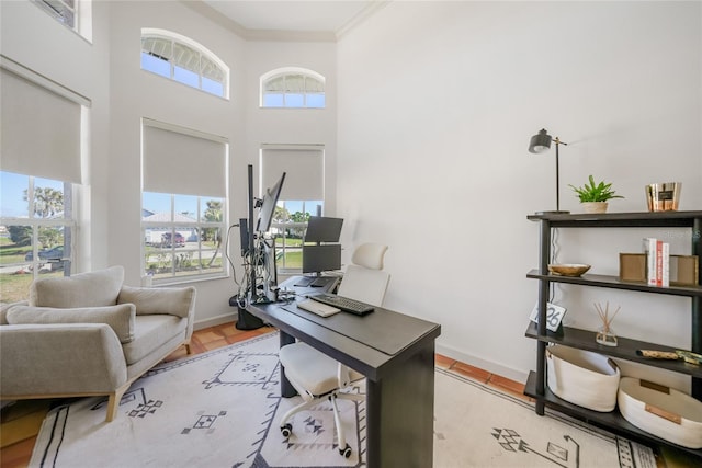 office area with crown molding, plenty of natural light, a towering ceiling, and light hardwood / wood-style floors