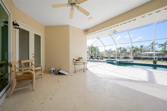 view of swimming pool with glass enclosure, ceiling fan, and a patio