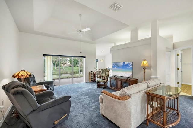 living room featuring ceiling fan, a raised ceiling, a towering ceiling, and carpet floors