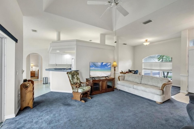 living room featuring ceiling fan, carpet, and a high ceiling