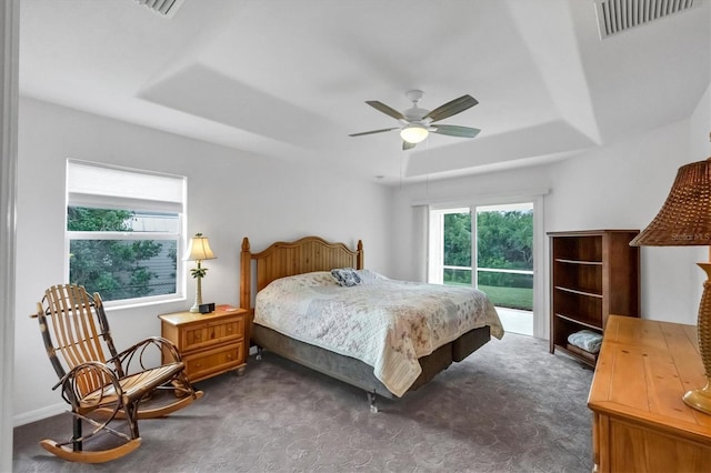 bedroom featuring a raised ceiling, ceiling fan, dark colored carpet, and access to outside