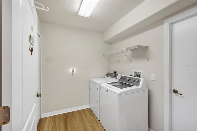 laundry room with light hardwood / wood-style floors and washing machine and clothes dryer