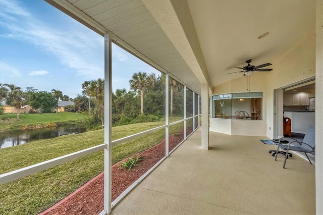 unfurnished sunroom featuring a water view, vaulted ceiling, and ceiling fan